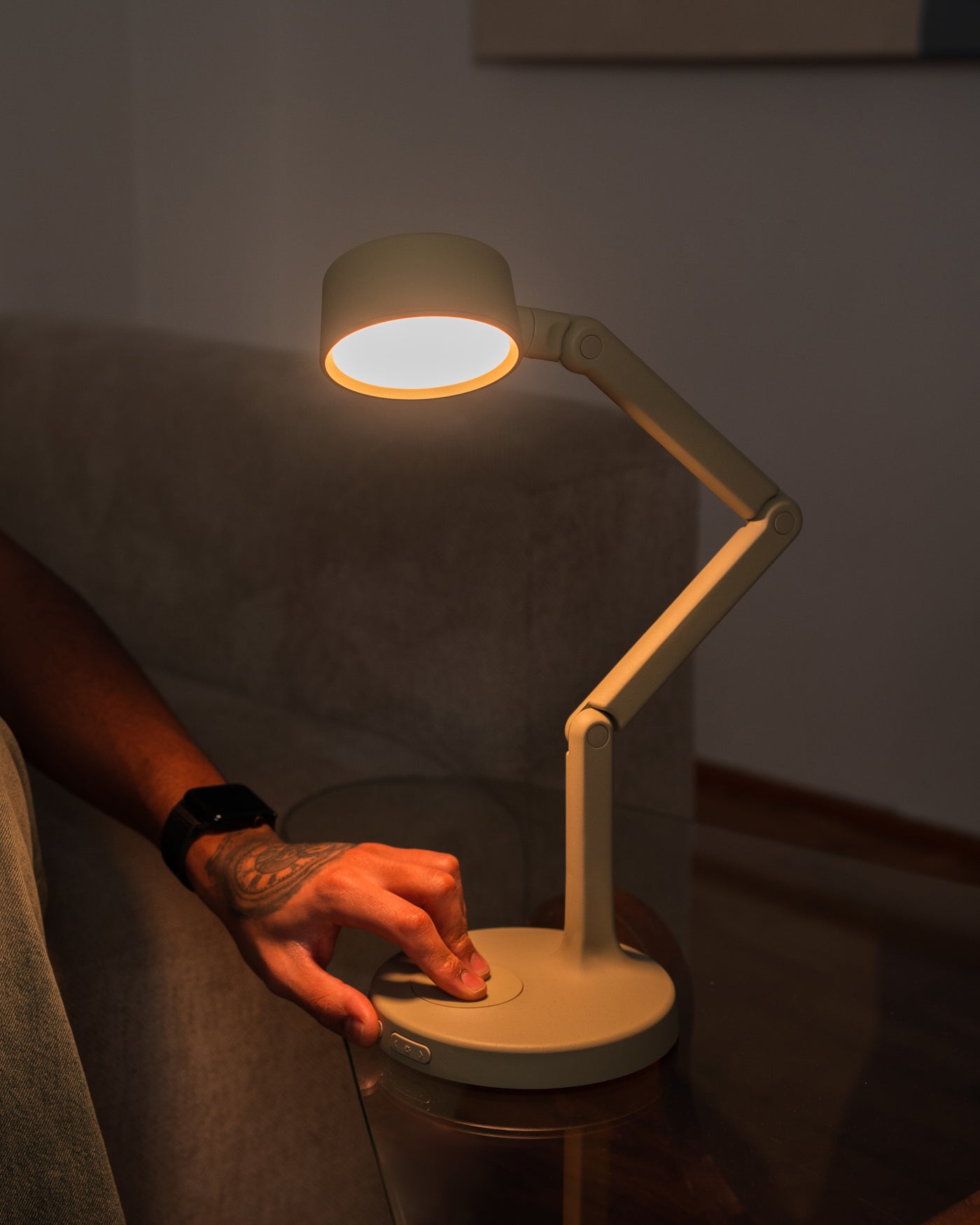 Person using a rechargeable desk lamp in a dimly lit room
