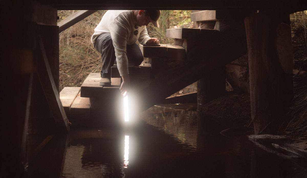 Man holding a Lume Cube RGB Tube Light just above the water, lighting up the surface
