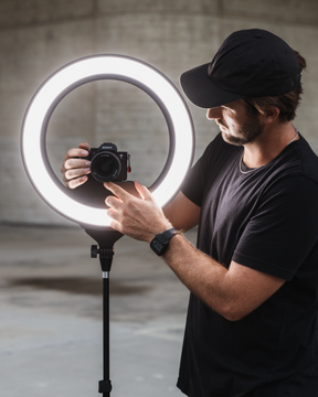 A man adjusting a camera mounted to a Ring Light Pro LC-RINGPRO-CR