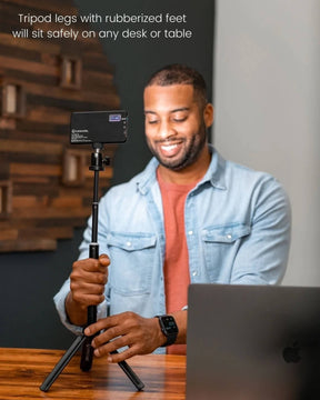 Man setting up Lume Cube's Broadcast Lighting Kit beside laptop to illuminate his face and show stability of rubberized feet. LC-SB-DLX