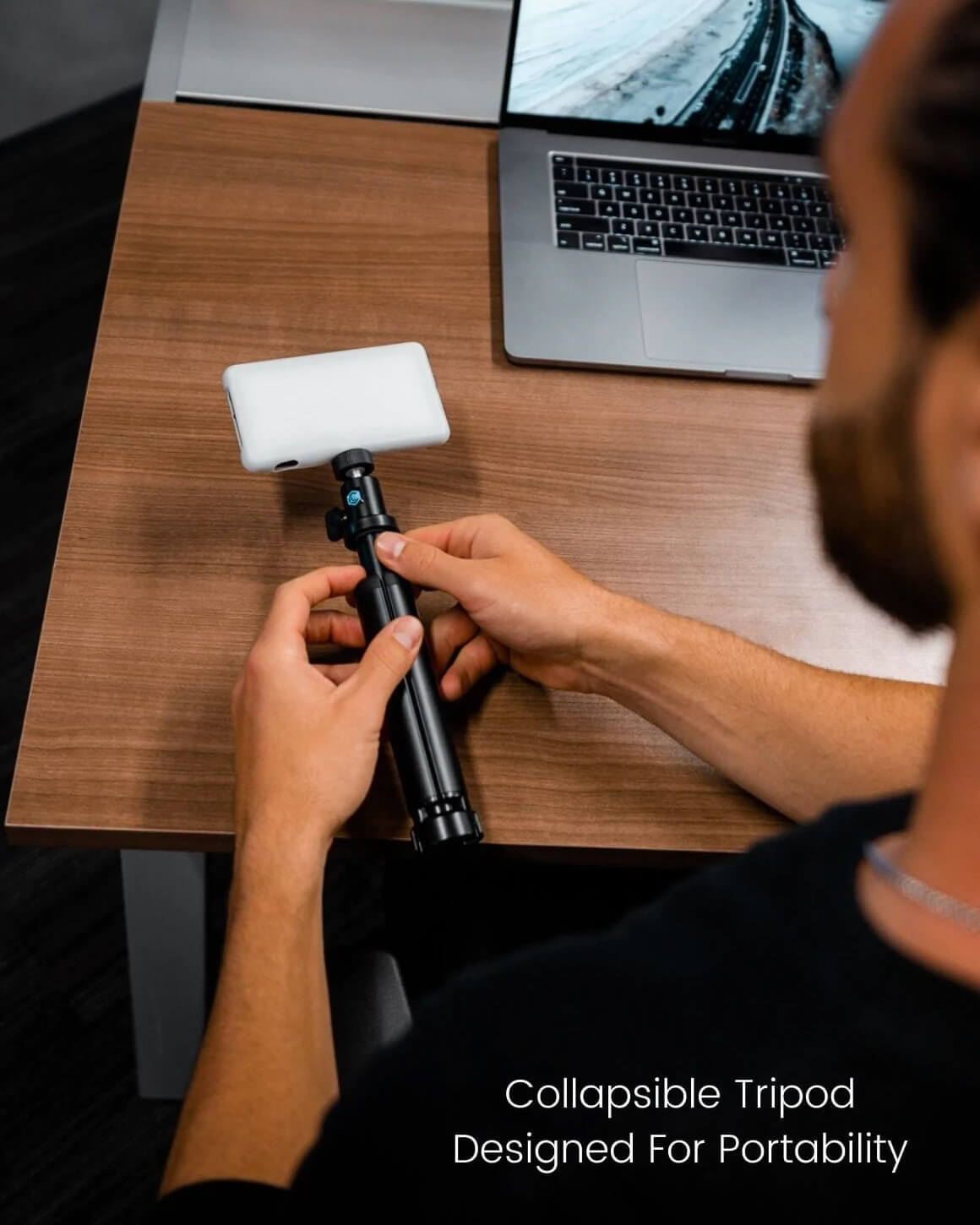 Man at desk holding fully-collapsed Lume Cube Broadcast Lighting Kit with Silicone Diffuser. LC-SB-DLX
