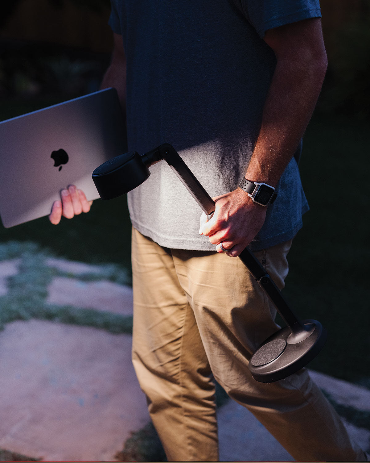 Person holding a macbook with a portable LED desk lamp