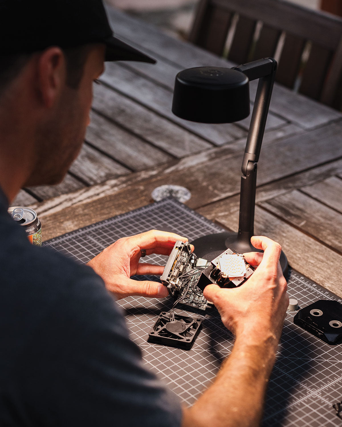 Person working on electronic components with a portable desk lamp on a wooden table