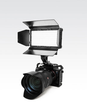 Camera with RGB Panel Pro and black metal 4-slat barn doors mounted on top.