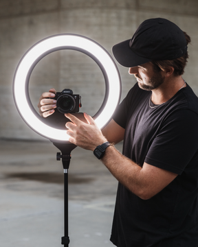 A man adjusting a camera mounted to a Ring Light Pro
